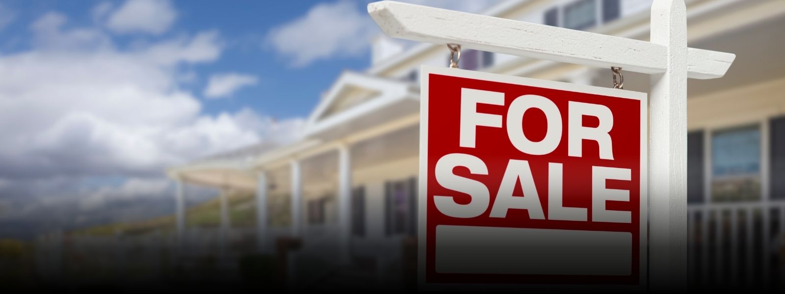 For Sale sign in front of a blurred home